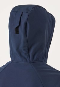 Navy blue hooded jacket with visible stitching and a black Velcro strap on the back of the hood against a plain background.