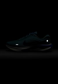 Černá běžecká obuv Nike s texturovaným svrškem, reflexními prvky a měkkou podrážkou. Obsahuje logo na boku a elegantní design.