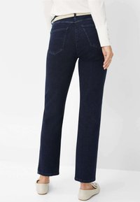 Jeans di denim blu scuro con un design a gamba dritta. Presentano due tasche posteriori e una vita classica. Texture liscia con hardware minimale.