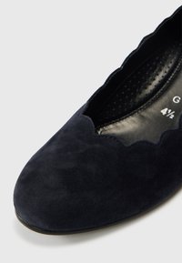 Granatowy baletowy płaski but z zamszu z falistym brzegiem, z zaokrąglonym noskiem i gładką, teksturowaną powierzchnią. Czarna perforowana wkładka.