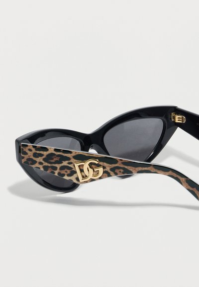 Μαύρα γυαλιά ηλίου cat-eye με σκούρους φακούς, βραχίονες με τύπωμα λεοπάρδαλης και ένα χρυσό λογότυπο "DG" στο πλάι.