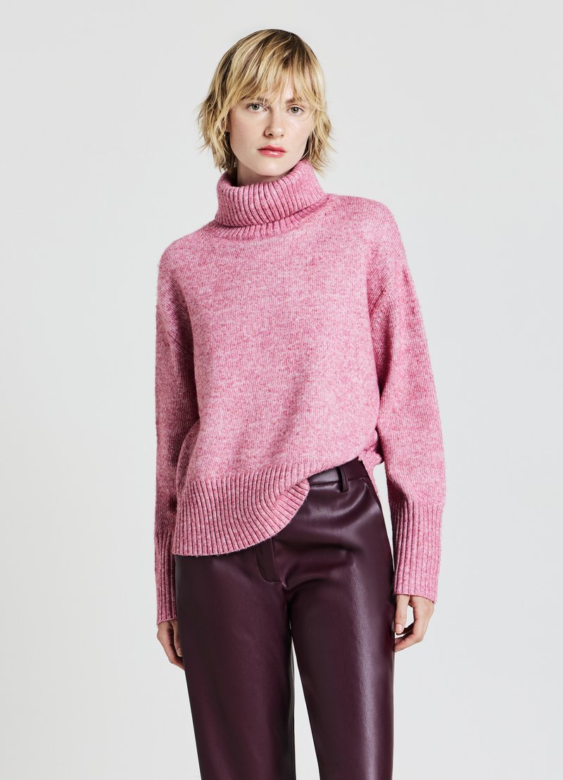 Rosa Rollkragenpullover mit lockerer Passform, gerippten Bündchen und Saum, mit einer strukturierten Oberfläche. Kombiniert mit dunkellila Lederhosen.