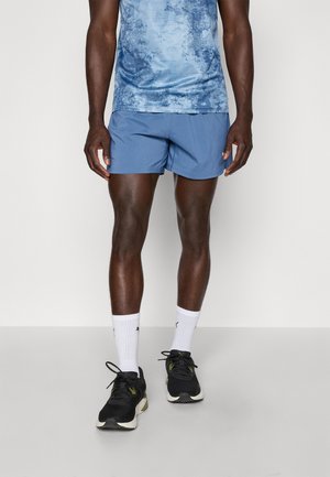 Blauw sportief tanktop met een gestructureerd patroon, gecombineerd met effen blauwe short, zwarte sneakers en witte crew sokken.