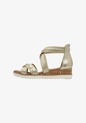 Sandali da donna metallici oro con cinturini incrociati, tacco a bassa zeppa, dettaglio in sughero e suola in gomma testurizzata. Cerniera laterale per un facile utilizzo.