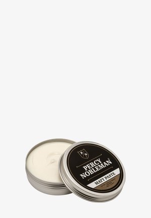 Boîte métallique ronde ouverte du produit coiffant Percy Nobleman Matt Paste avec crème blanche à l’intérieur et étiquette noire sur le couvercle.