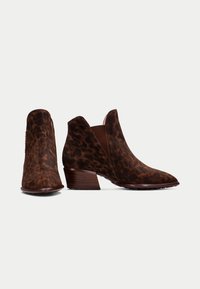 Botas de tobillo de estampado de leopardo marrón en suave ante, con un bajo tacón apilado y cortes laterales para facilitar el calzado.