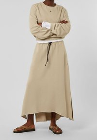 Sweat-shirt beige à col rond, coupe décontractée et épaules tombantes, accompagné d'une jupe maxi beige assortie avec une taille à cordon de serrage.