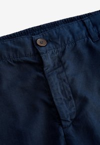 Pantaloni bleumarin cu talie elastică, închidere cu buton și buzunare laterale. Materialul pare moale, având o ușoară strălucire.