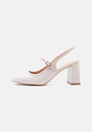Chaussure femme slingback couleur crème avec talon bloc et bride réglable avec boucle dorée, vue de côté sur fond blanc.