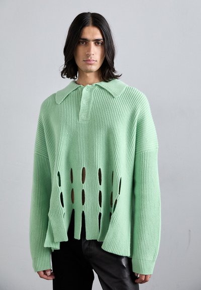 Suéter de punto verde menta con cuello de solapa y detalles recortados a lo largo del dobladillo. Mangas de gran tamaño y textura acanalada.
