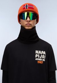 Sort fleece halsvarmer, orange strikket hue med Norges flag, og reflekterende solbriller. T-shirten har et stort hvidt og orange tekstdesign.