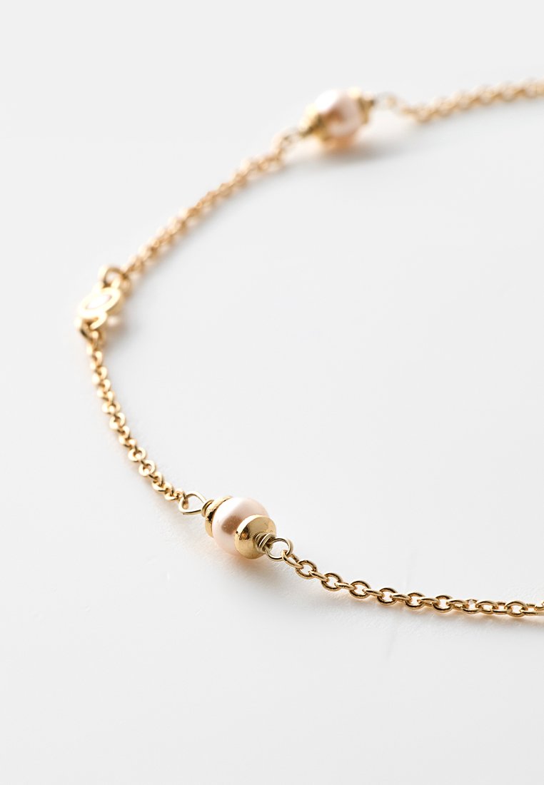 Bracelet en chaîne dorée mettant en vedette de petites perles rondes de couleur crème et un fermoir en forme de homard, affichant un design délicat et simple.