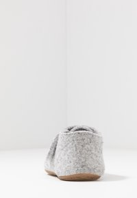 Gråa tofflor i mjukt material, rundad form och gummisula. Har en enkel design med minimal detaljering.