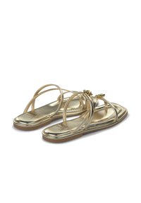 Goldene flache Sandalen mit mehreren dünnen Riemen und einem tropfenförmigen Schmuckelement an der Vorderseite. Glatte metallische Oberfläche und gepolsterte Innensohle.