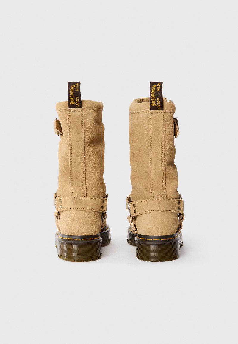 Bottines en suede beige avec un bout rond, deux sangles latérales et des tirants jaunes à logo. Semelle en caoutchouc texturé et épais.
