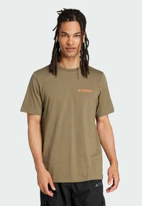 Oliven grøn T-shirt med kortærmer lavet af letvægtsstof, der har et lille orange "TERREX" logo på brystet.