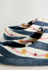 Pantofole in pile con motivo a righe blu navy e bianche. Accenti comprendono stelle rosa e oro, tessuto morbido e suola imbottita per il comfort.