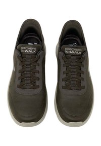Scarpe nere Skechers GOWALK con tomaia in tessuto liscio, punta rotonda, lacci testurizzati e suola in gomma bianca. Logo visibile sulla linguetta.
