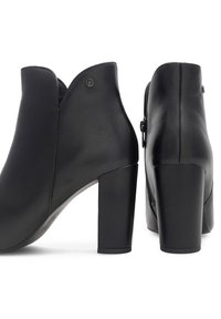 Čierne kožené členkové čižmy s výrezom v tvare V, so širokým blokovým podpätkom a bočným zipsom pre jednoduché obúvanie. Hladká textúra a jemný detail loga.