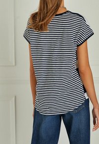 Camiseta a rayas con rayas horizontales en navy y blanco, manga corta y dobladillo redondeado, combinada con unos vaqueros azul de corte holgado.
