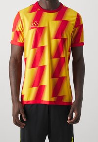 Kortärmad prestationströja i gult och rött, med ett zickzackmönster och en ribbad rundhalsning.