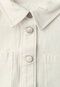 Veste en denim blanche avec col, poches avant et boutons-pression métalliques gravés "STREET ONE STUDIO."