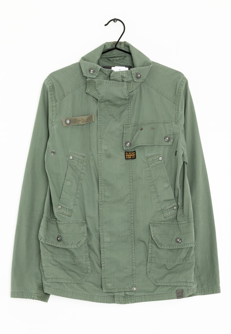 Olivově zelená bunda vyrobená z texturované tkaniny, se stojáčkem, několika předními kapsami a akcenty na patentky.