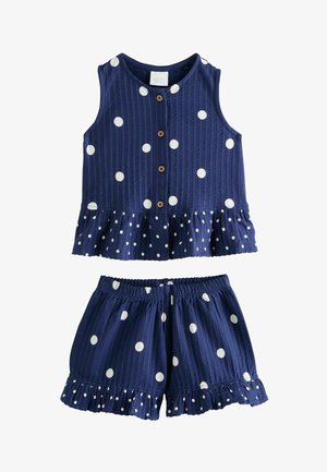 Tamsiai mėlynas berankovis komplektas su šortais, baltais taškeliais, mediniais mygtukais ant viršaus ir raukšlėtomis apačiomis.