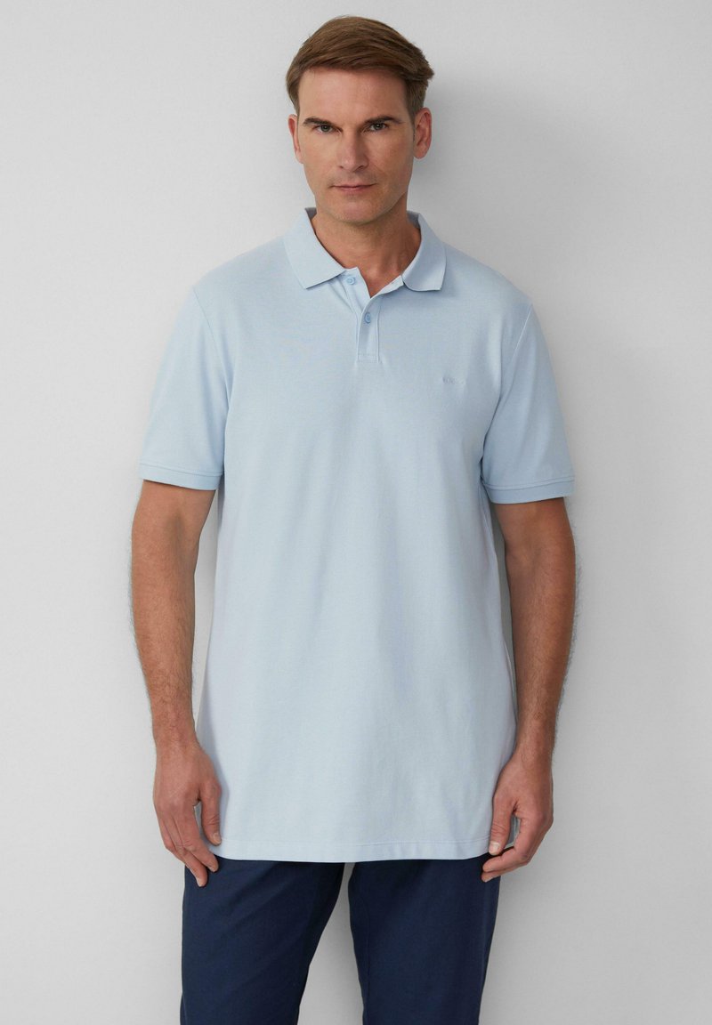 Hellblaues Poloshirt mit Kragen und kurzen Ärmeln. Verfügt über einen strukturierten Stoff und ein kleines Logo auf der linken Brust.