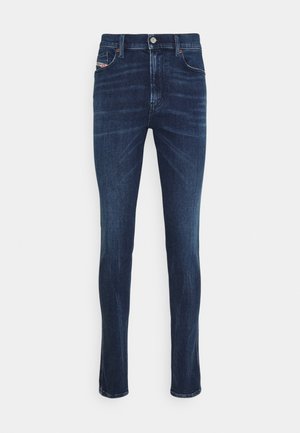 Donkerblauwe slim-fit spijkerbroek met voorzakken, riemlussen en knoopsluiting, afgebeeld tegen een witte achtergrond.
