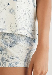 T-Shirt und Shorts mit einem blauen astronomischen Muster auf cremefarbenem Hintergrund, mit einem geschichteten Saumdetail und glatter Textur.