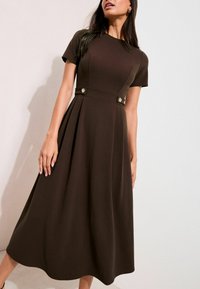 Brązowa sukienka midi z dopasowanym gorsetem, krótkimi rękawami i plisowanym dołem. Ozdobiona złotymi guzikami w talii, wykonana z gładkiej, teksturowanej tkaniny.