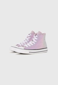 Un par de zapatillas altas iridiscentes de color púrpura con suelas de goma blancas y cordones blancos sobre un fondo blanco liso.