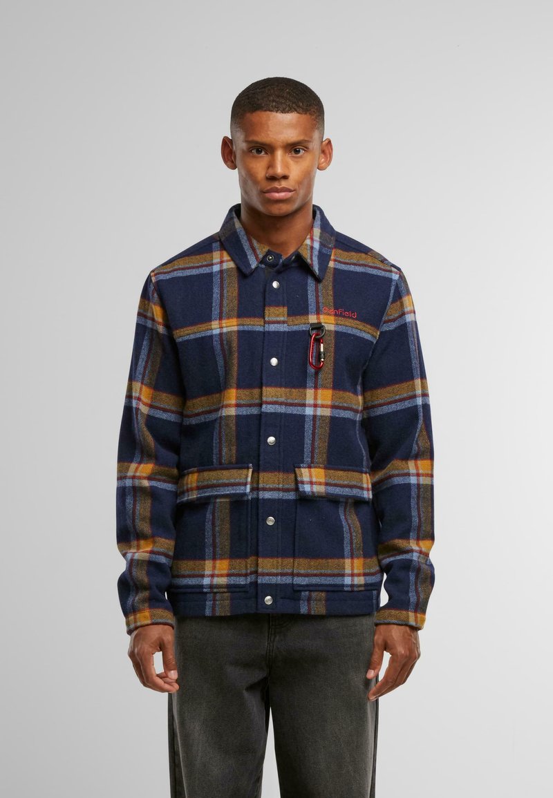 Mørkeblå rutete jakke med oransje og lyseblå striper, med trykknapper, brystlomme med karabinkrok og strukturert design.