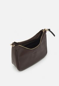 Petit sac à main en cuir brun foncé avec une fermeture éclair dorée partiellement ouverte, montrant un intérieur sombre et des fentes pour cartes à l'intérieur.