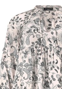 Blusa rosa chiaro con stampa paisley e fiorata nera. Presenta un colletto alla mandarino, scollatura a chiave e maniche volanti; tessuto morbido.