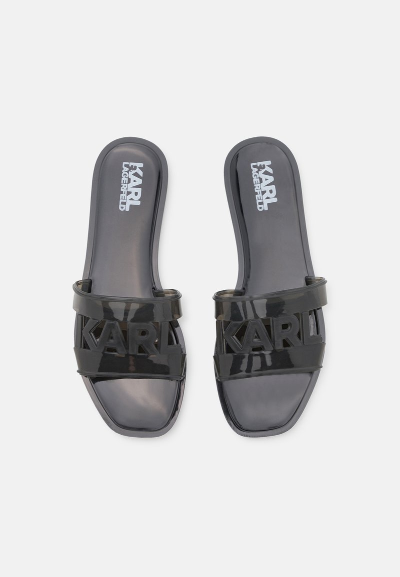 Schwarze Gummisandalen mit breitem Riemen, auf dem das Logo "KARL" deutlich sichtbar ist. Flache Sohle mit glänzender Oberfläche.
