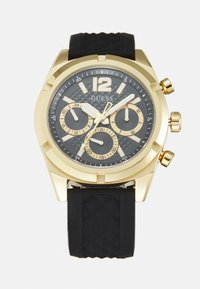 Goldfarbene Chronographuhr mit einem strukturierten schwarzen Zifferblatt und Gummiband. Verfügt über drei Teilzifferblätter, große Zahlen und ein markantes Design.