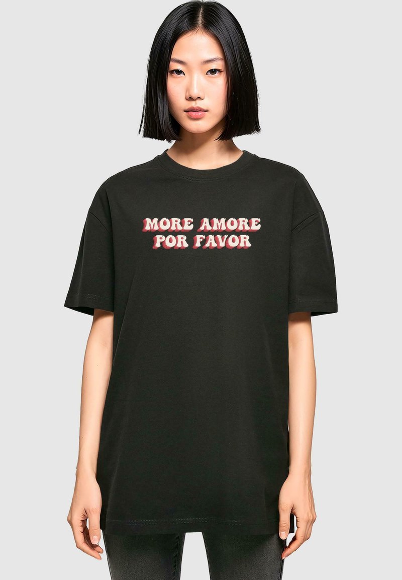 T-shirt in cotone nero con la frase "MORE AMORE POR FAVOR" in caratteri bianchi e rossi, in grassetto e stilizzati. Fit rilassato, maniche corte.