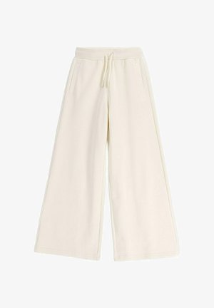 Kremowe szerokie spodnie dresowe z elastycznym pasem, sznurkiem do wiązania i bocznymi kieszeniami z rozcięciami, rozłożone na płasko na białym tle.