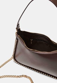 Borsa a mano in pelle marrone scuro con rifiniture in perline dorate e tracolla a catena, apertura con zip superiore che rivela una tasca interna con zip su sfondo chiaro.