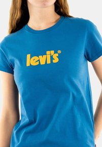 Camiseta de algodón azul con un gran logo amarillo de "levi's" en el frente, con un diseño clásico de cuello redondo y mangas cortas.