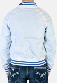 Lyseblå bomberjakke med ribbet krave med blå og hvide striber. Elastiske manchetter og talje, glat, skinnende materiale.