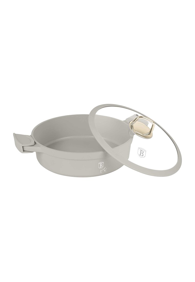 Casserole grise peu profonde avec une poignée sur un côté et un couvercle en verre transparent avec un bouton doré, incliné pour montrer l'intérieur de la casserole.