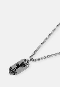 Colar de corrente prata com um pendente rectangular apresentando a silhueta de um lagarto preto, bordas detalhadas e um acabamento polido.