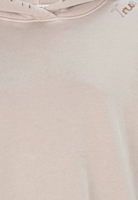 Lichtroze hoodie met een capuchon, geribbeld stof en gedeeltelijke geborduurde tekst "True" bij de halslijn.