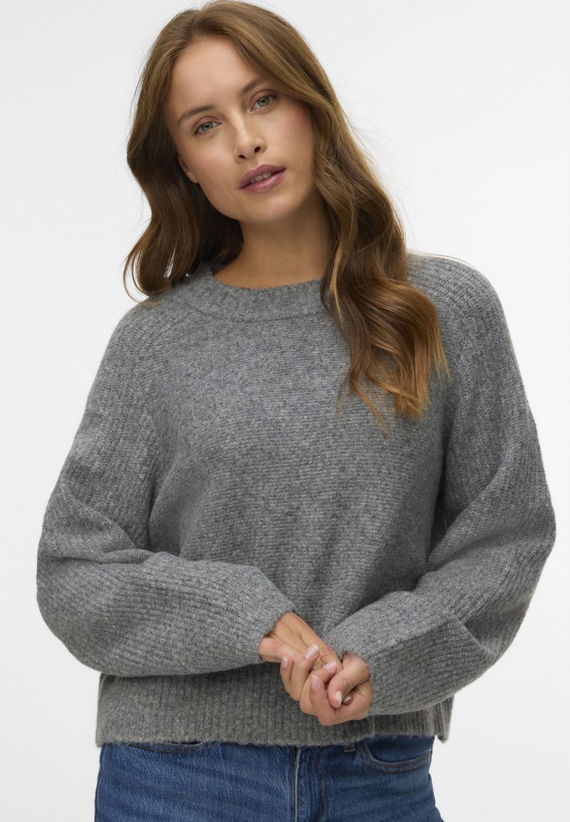 Maglione grigio in maglia con scollo rotondo, spalle scese, polsini a coste e orlo leggermente accorciato. Tessuto morbido e vestibilità ampia.