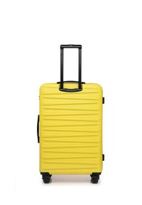 Gele harde koffer met een ribbelstructuur, zwarte uitschuifbare handgreep en vier zwarte wielen voor mobiliteit.