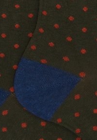 Dark green socks with small red polka dots and solid blue heels, knitted texture visible in close-up view.