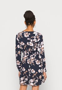 Vestito floreale con maniche lunghe, base blu navy, fiori rosa chiaro e beige, vita elasticizzata e vestibilità morbida.